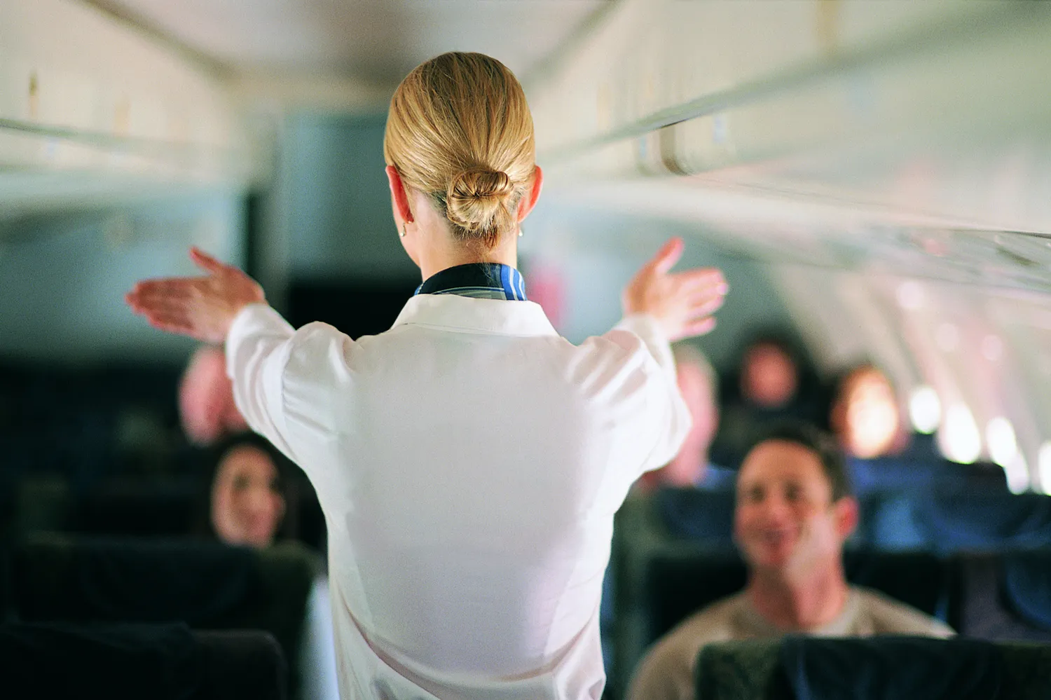 A flight attendant in uniform demonstrating safety protocols on an aircraft.