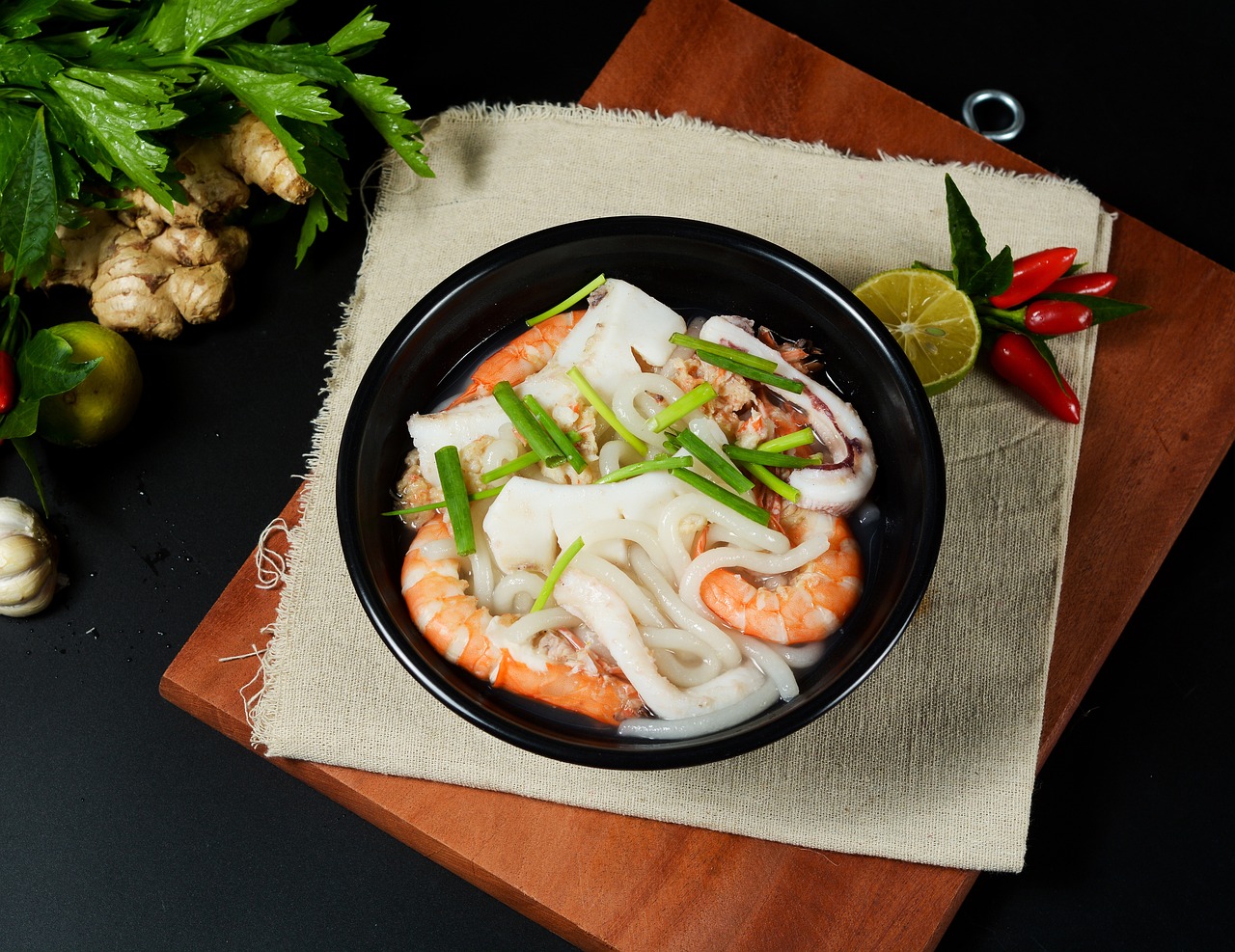 A steaming bowl of traditional Vietnamese pho with fresh basil and lime on a wooden table.