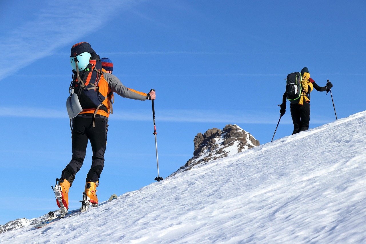 A professional mountain guide using a radio and checking snow conditions.