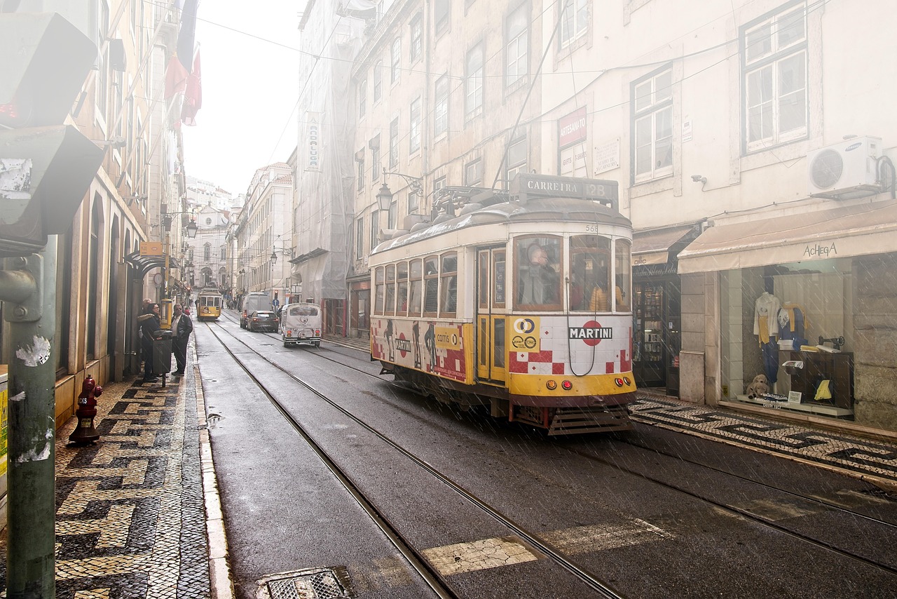 A classic yellow tram moving through the colorful, hilly streets of Lisbon, Portugal
