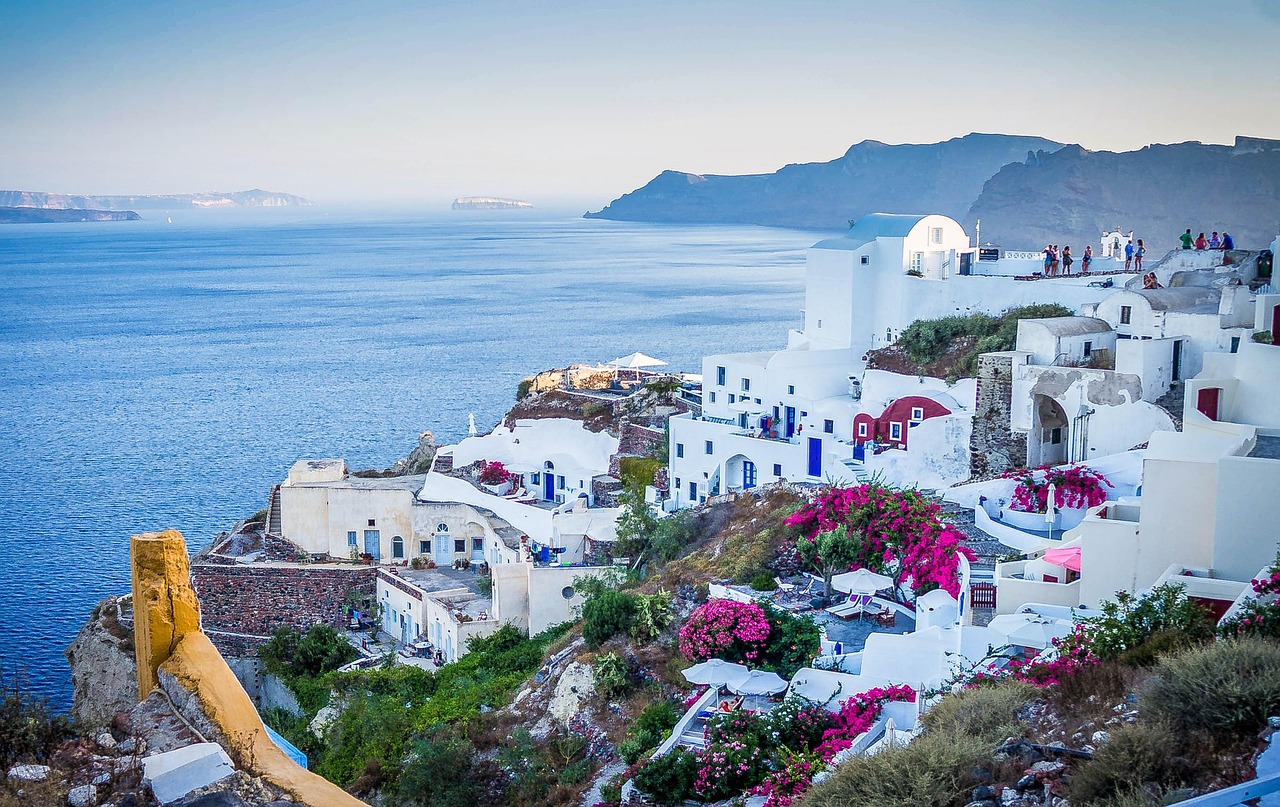 The white buildings of Oia overlooking the blue sea during a clear winter sunset.