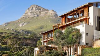 Modern white architecture of a luxury resort building in Cape Town with a person relaxing by the pool.