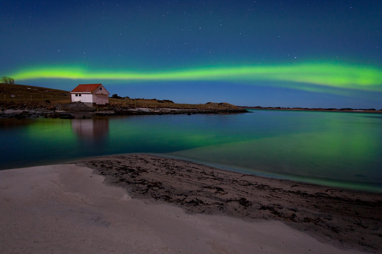 Bright green aurora borealis dancing over a snowy wooden cabin in the forest.