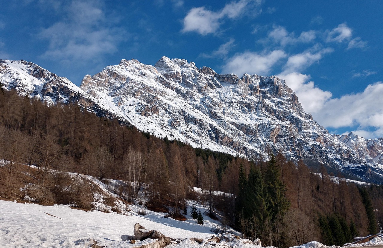 Jagged snow-capped mountain peaks of the Dolomites towering over an Alpine valley in Cortina.