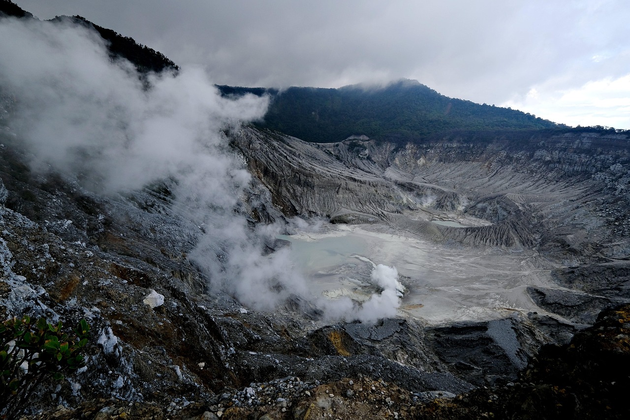 Active volcanic craters releasing white steam against a dark lava rock background.