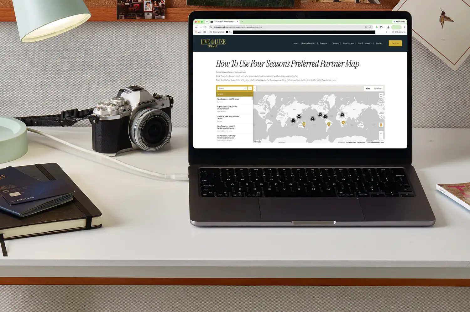 A laptop on a desk showing a Four Seasons Preferred Partner map interface next to travel accessories.