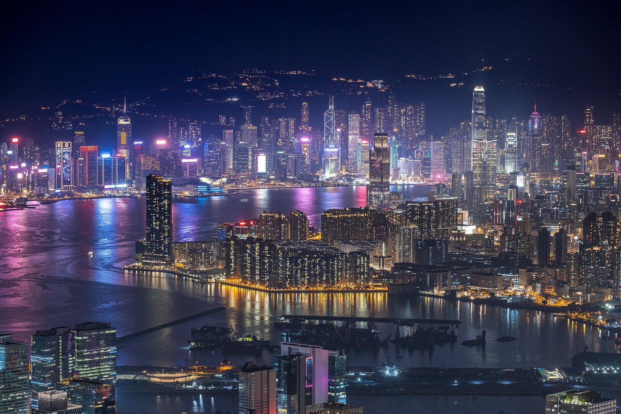 A narrow Hong Kong street at night illuminated by colorful neon signs.