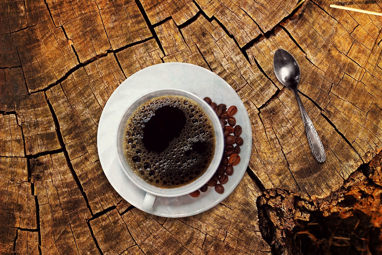 A cup of latte art and a slice of cake on a wooden cafe table