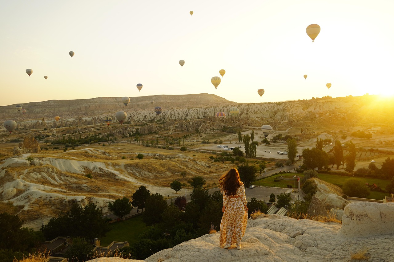 A colorful hot air balloon drifting over the rolling countryside and vineyards of Haute-Provence at dawn.
