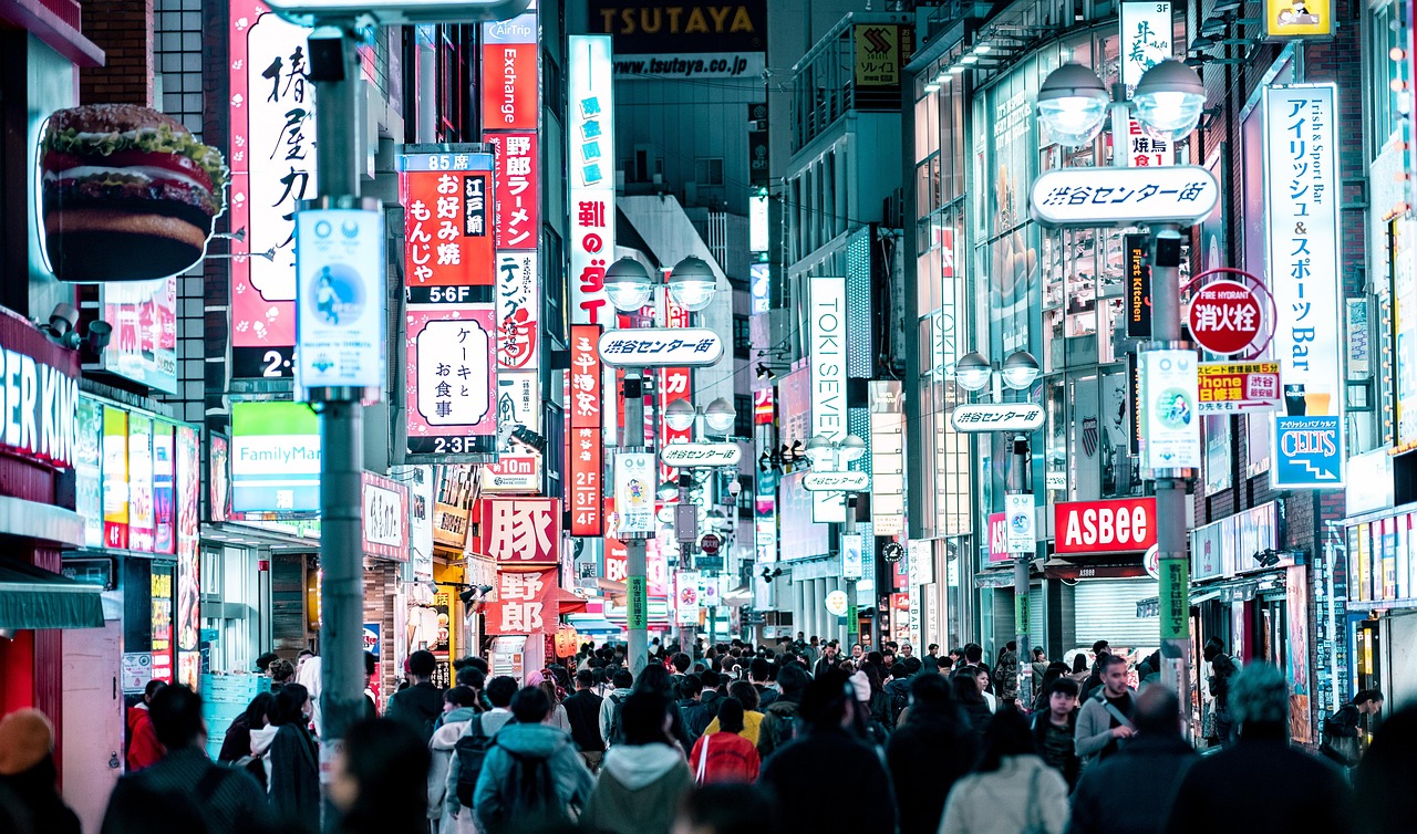 A vibrant Tokyo street filled with colorful neon signs and pedestrian activity.