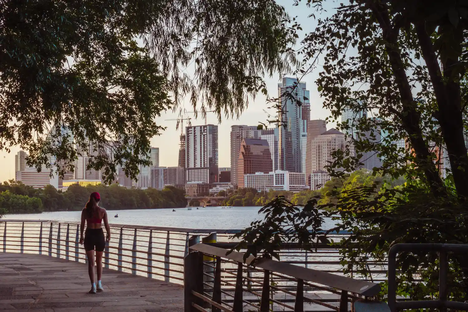 A pedestrian path along Lady Bird Lake with the Austin, Texas skyline in the background.
