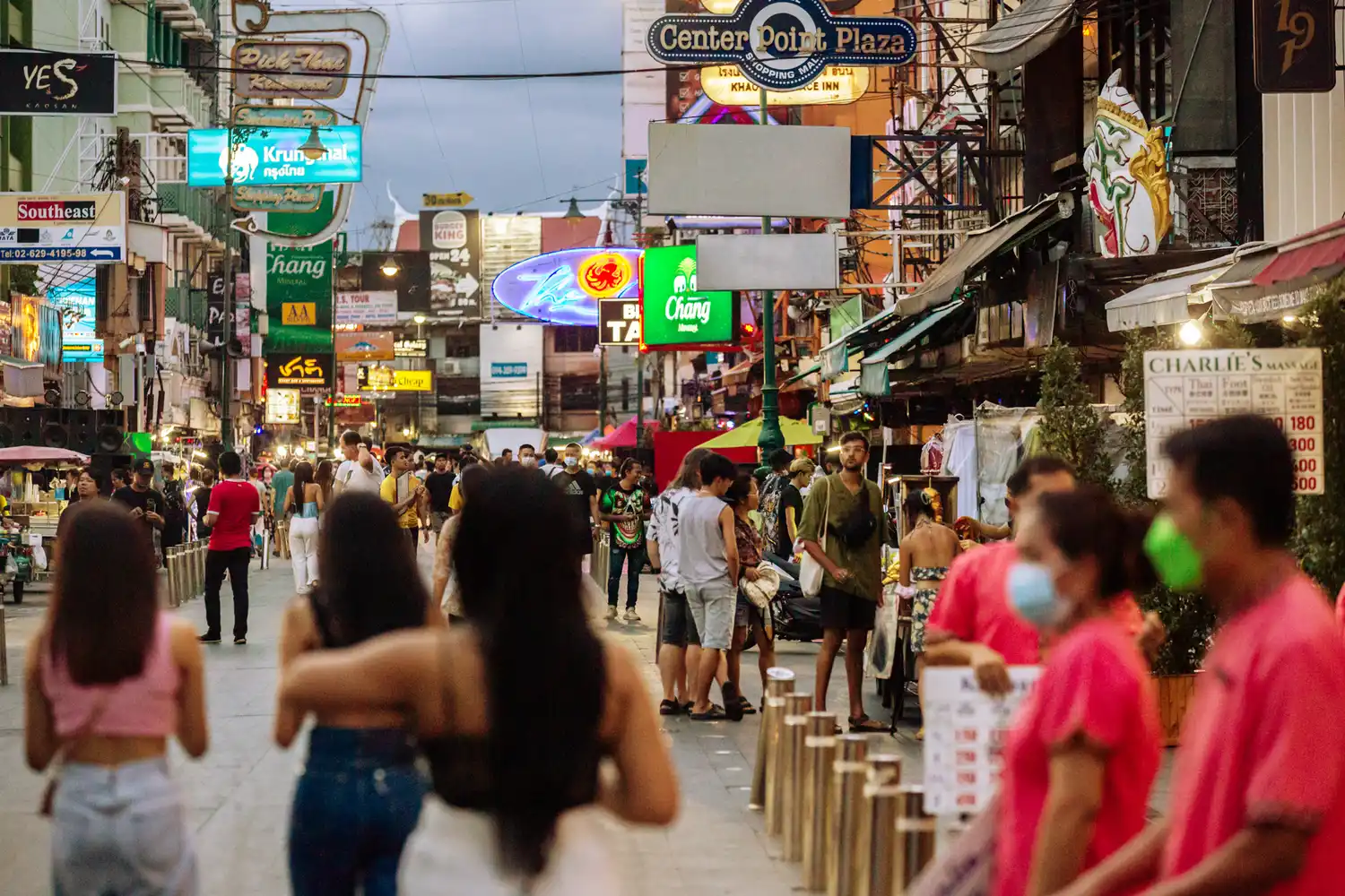 The bustling Khao San Road in Bangkok at night with bright neon signs and crowds.