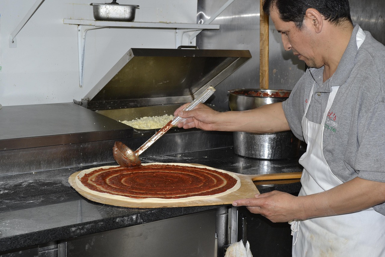 Italian chef teaching young children how to stretch pizza dough in a traditional kitchen.