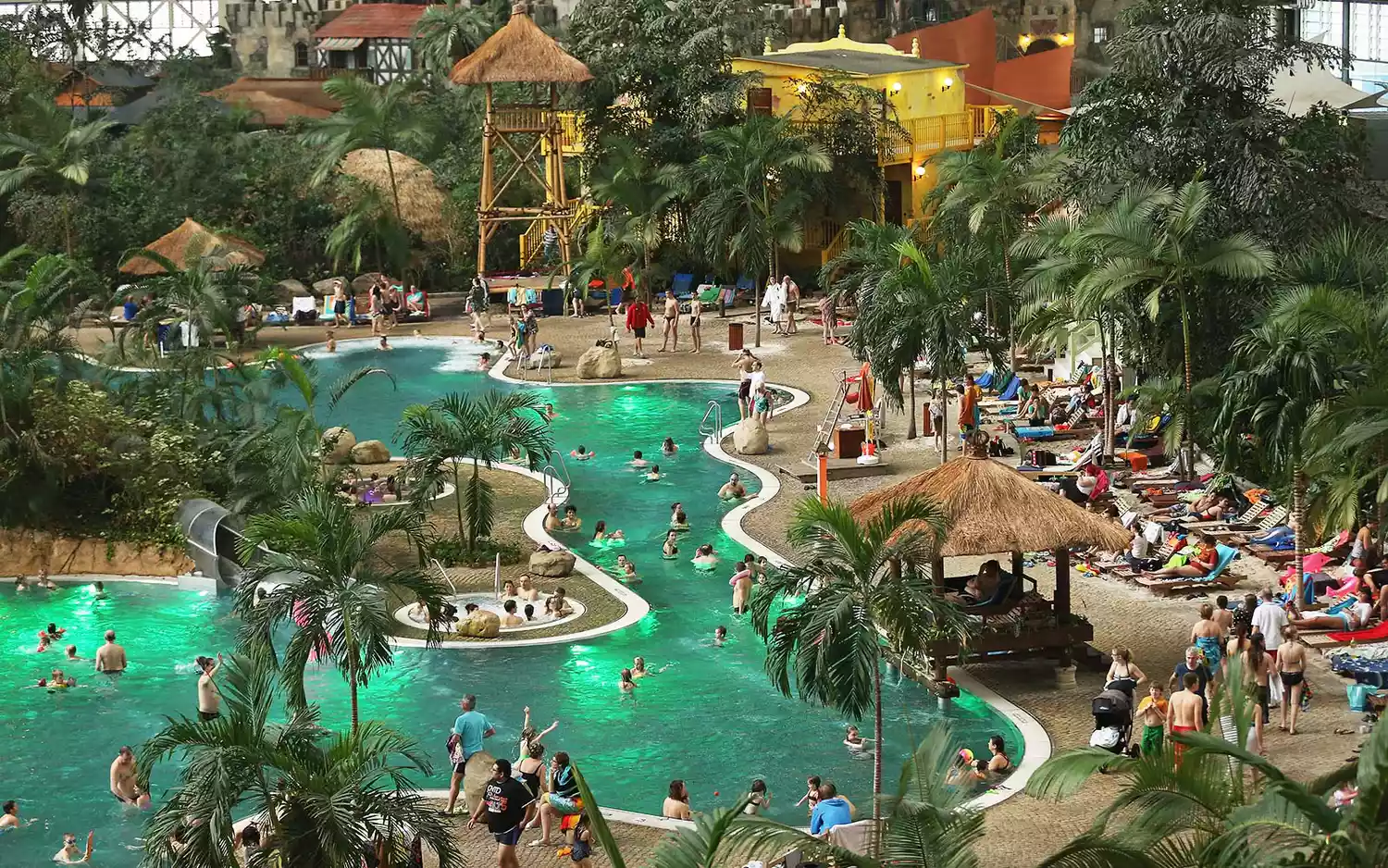 Crowds of visitors enjoying the sandy beaches and pools under the clear roof of the Tropical Islands resort.