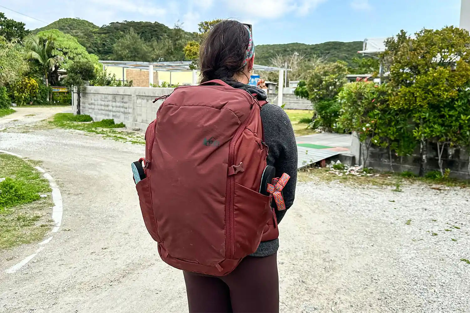 A traveler walking down a path in a neighborhood wearing a full-sized travel backpack.