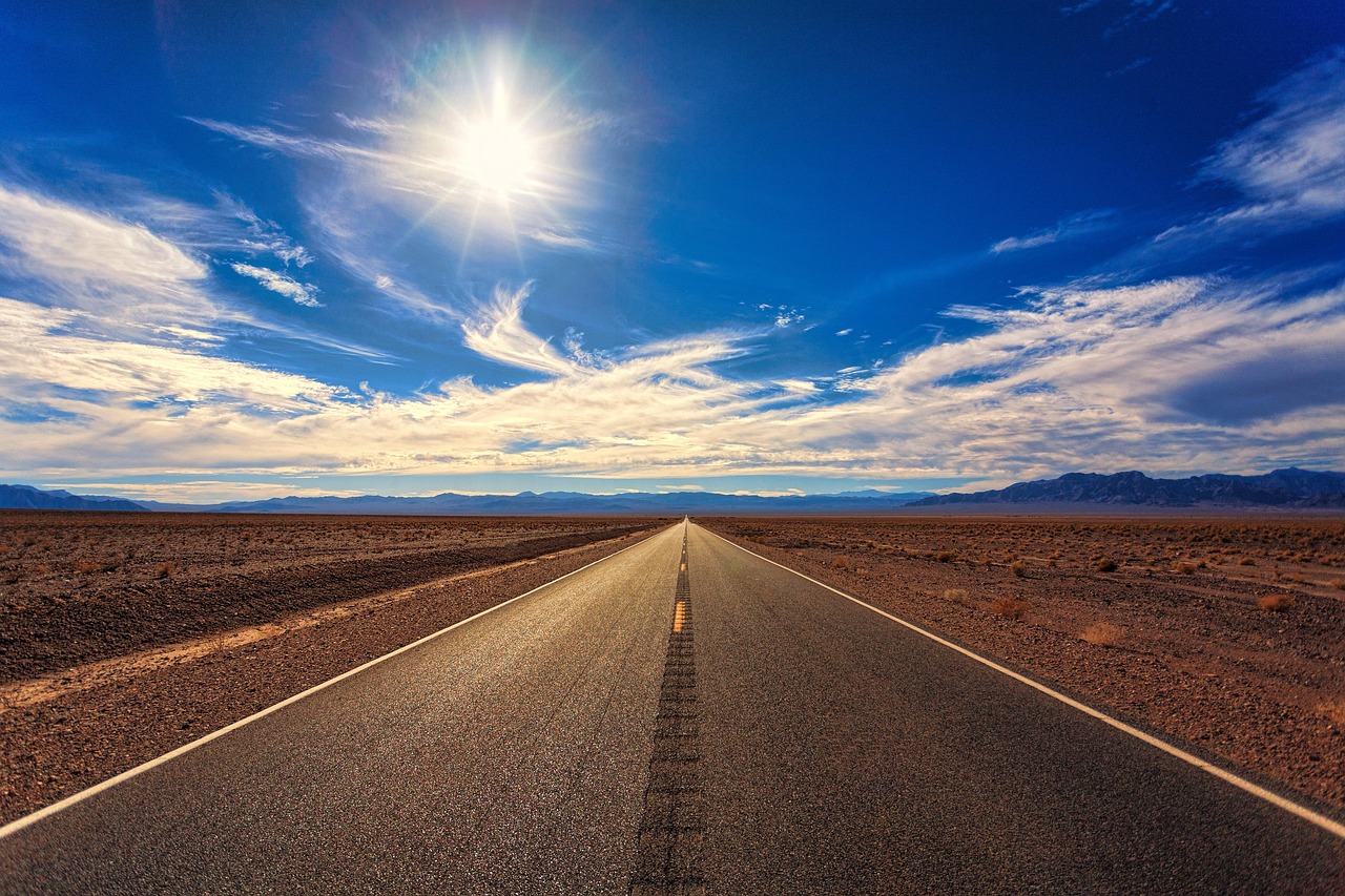A perfectly straight asphalt road disappearing into the flat horizon of the desert.