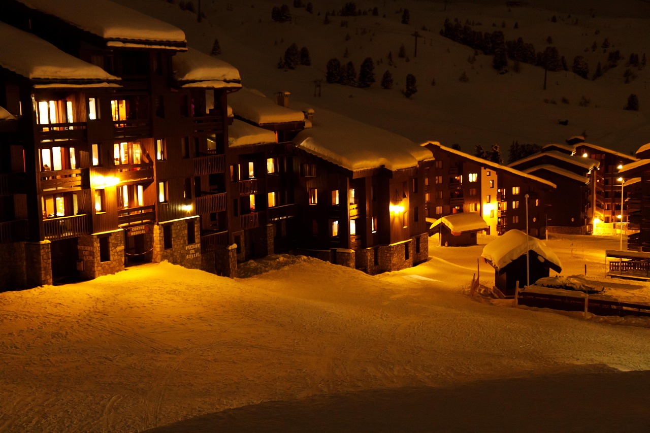 Skiers on a mountain slope at night illuminated by powerful floodlights.