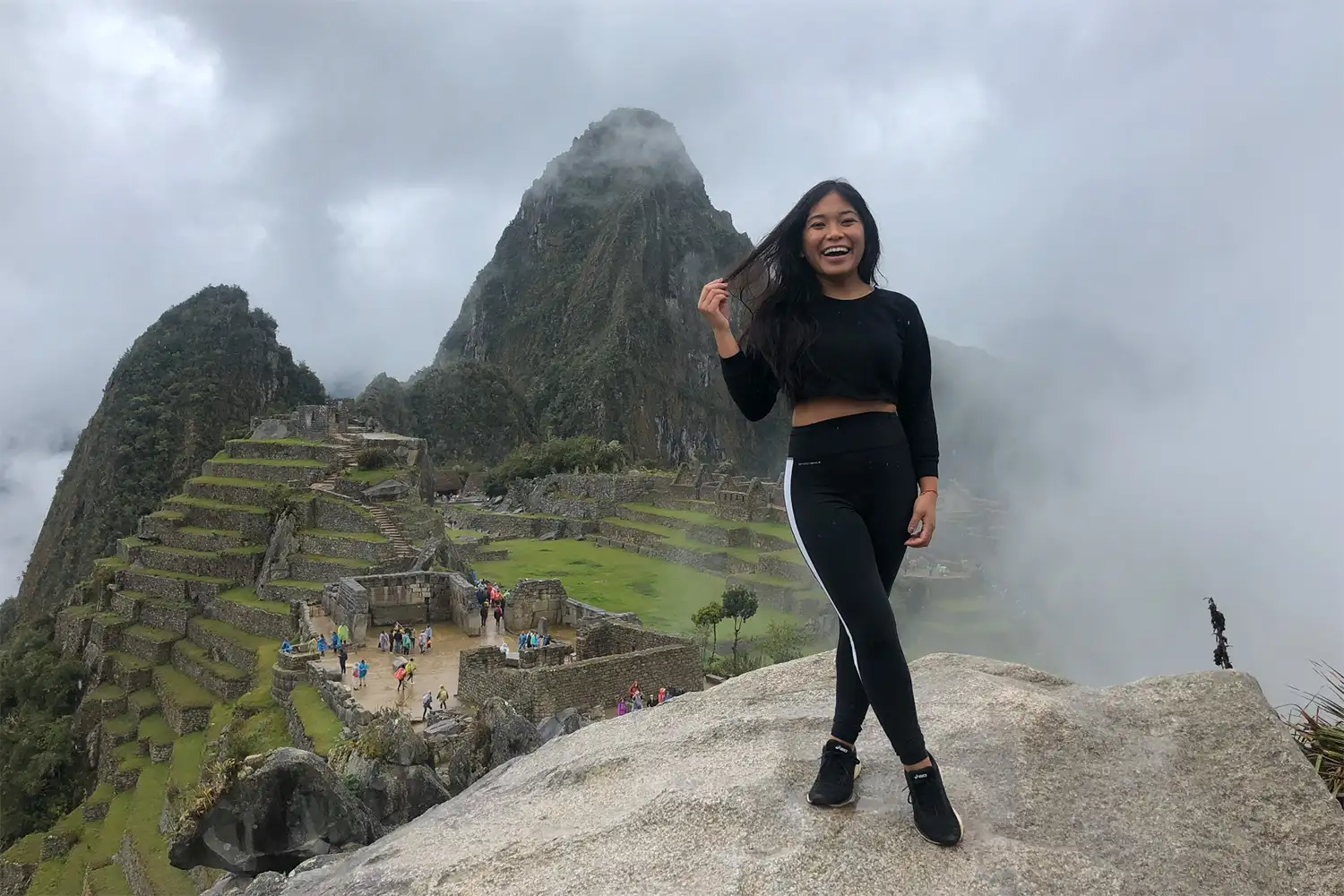 A traveler standing on a ridge looking out over the Machu Picchu citadel and Huayna Picchu mountain.