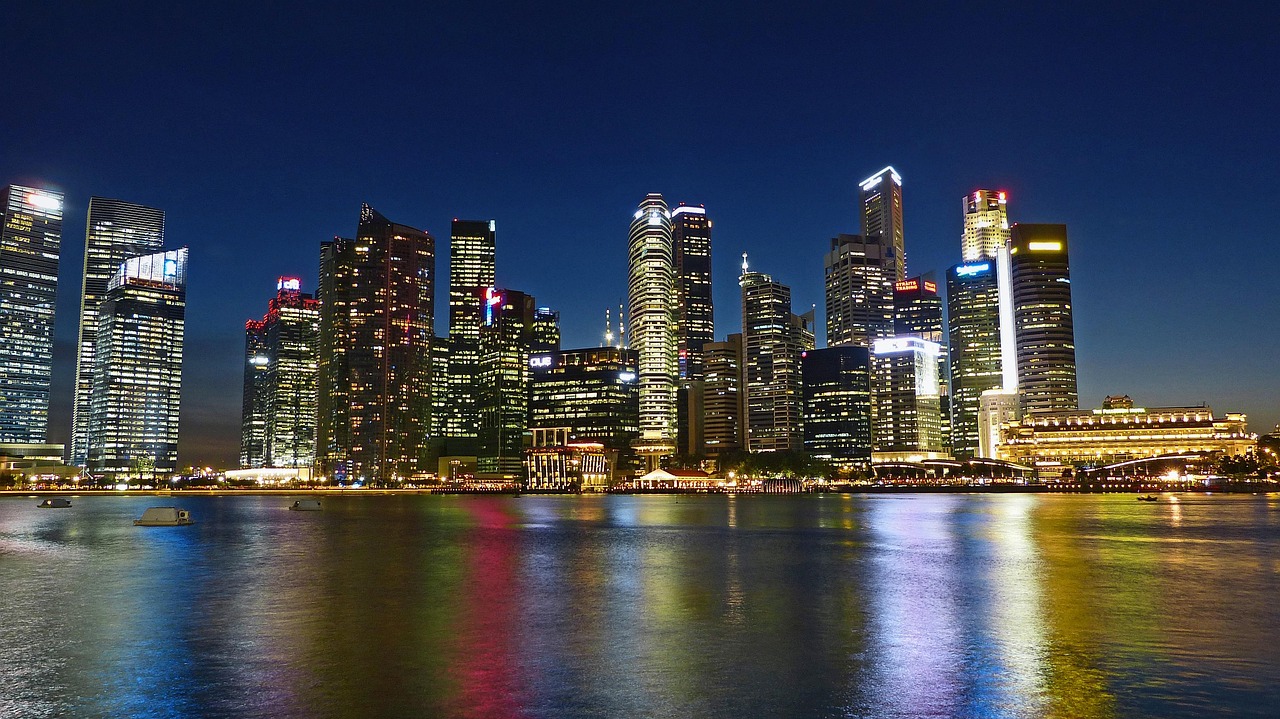 The Boston skyline illuminated at night reflected in the calm waters of the Charles River.