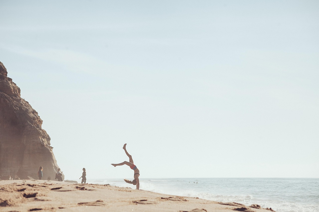 A traveler sitting on a beach during golden hour, fully protected and enjoying the view.