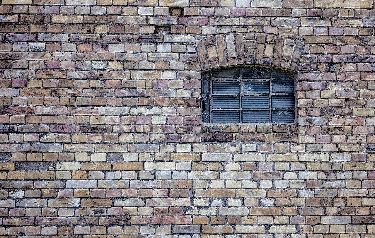 Exterior view of a historic brick prison building under a gray sky.