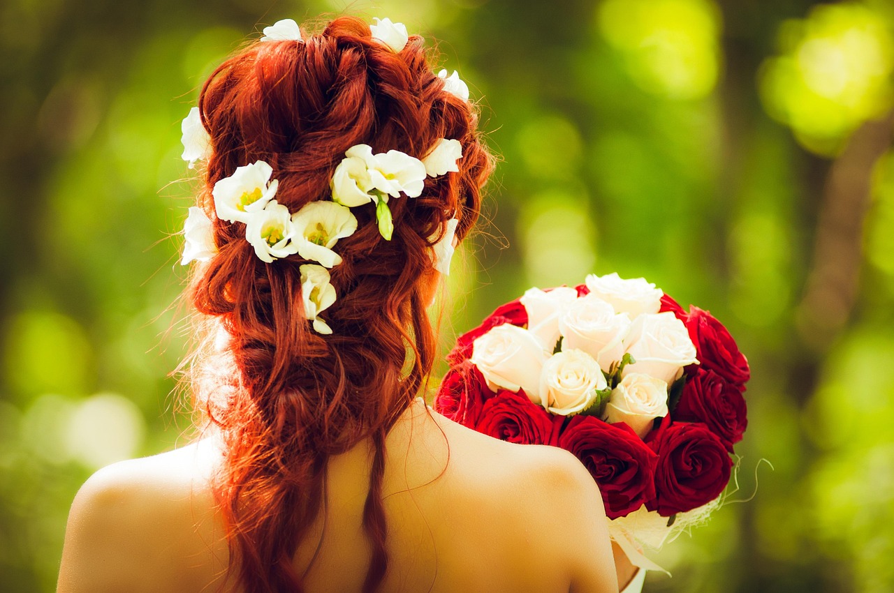 Elegant white floral arrangements and greenery on a long wooden wedding table.