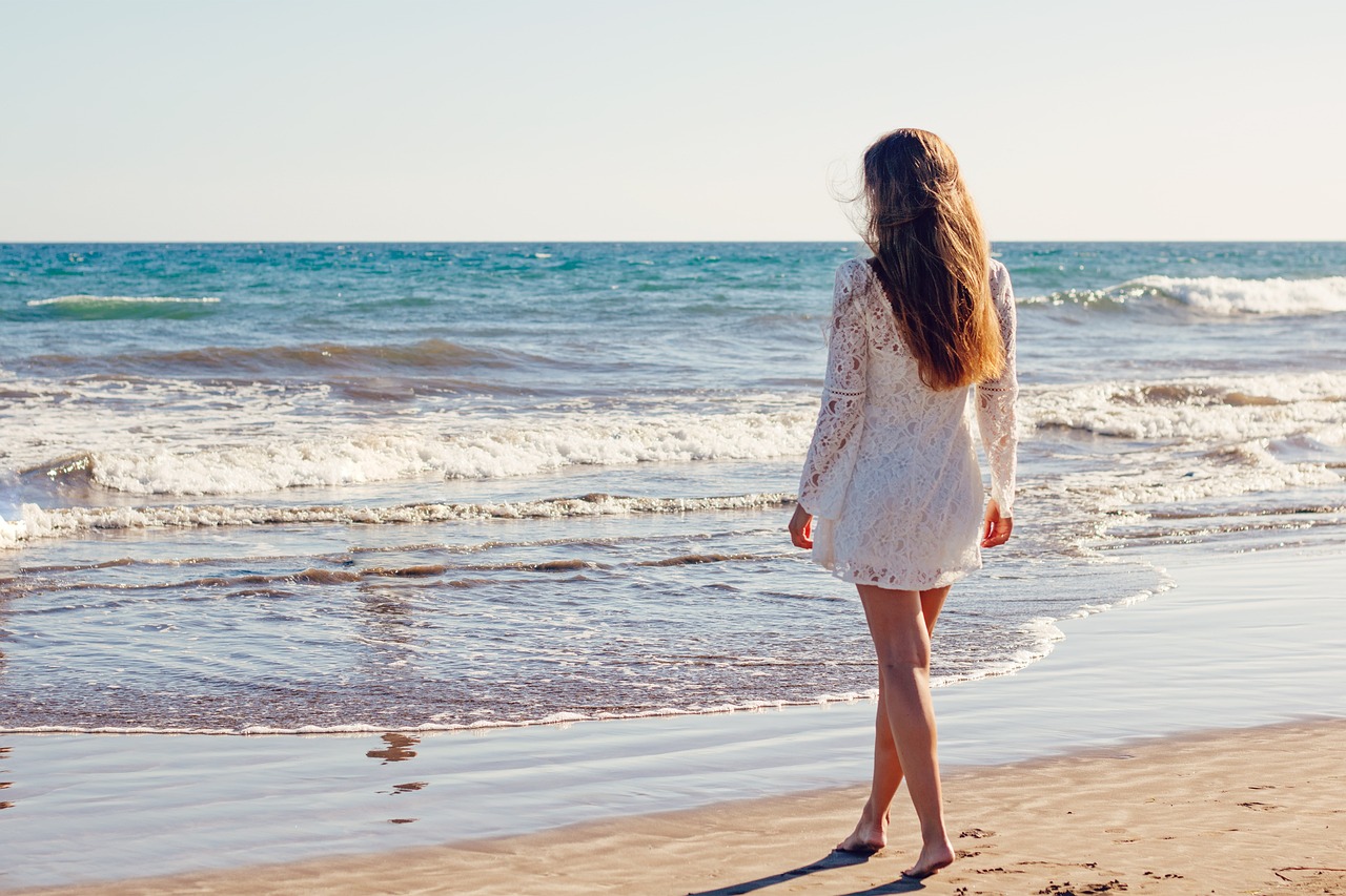 A woman wearing a mint green silk dress on a coastal boardwalk.