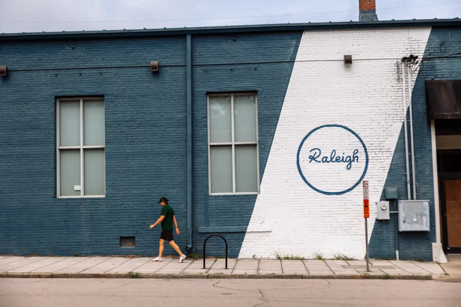 A person walking past a colorful mural in downtown Raleigh, North Carolina.