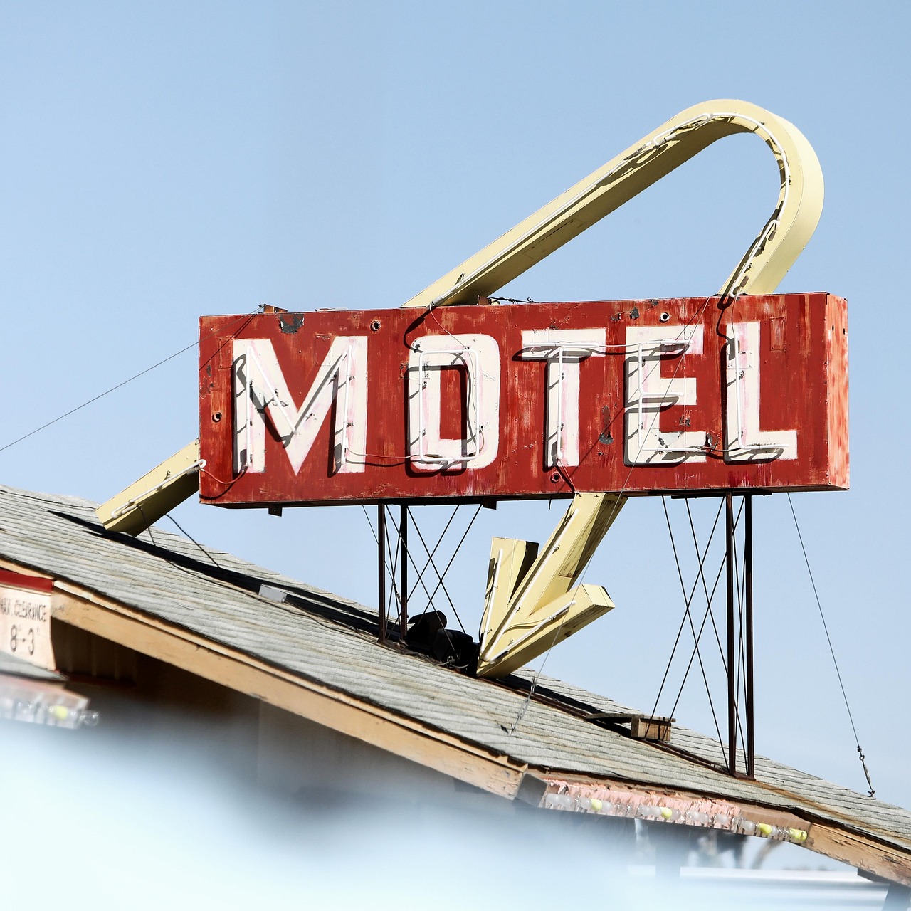 A vintage neon motel sign along a historic road at dusk.
