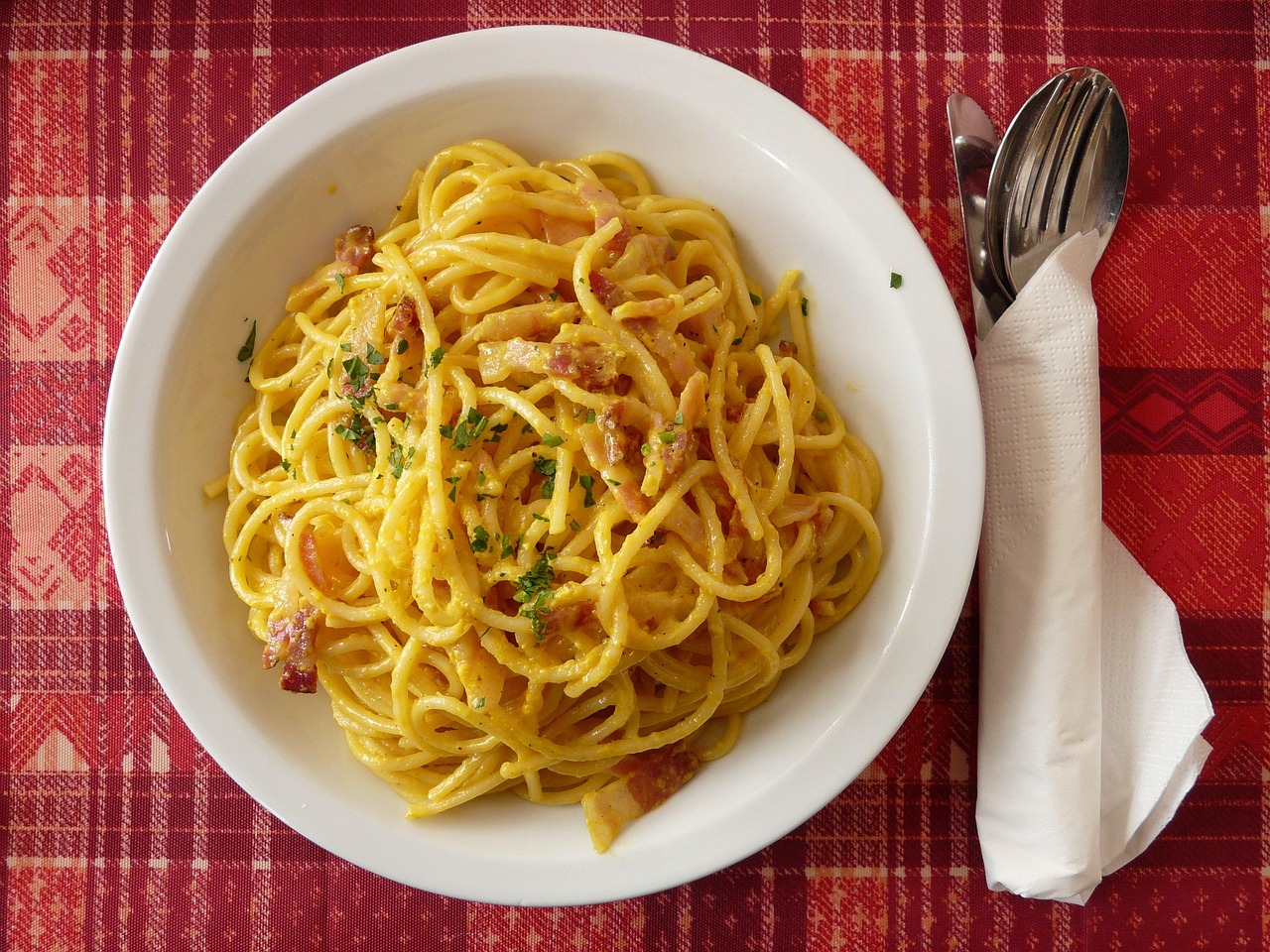 A close-up of authentic spaghetti carbonara with guanciale and black pepper.