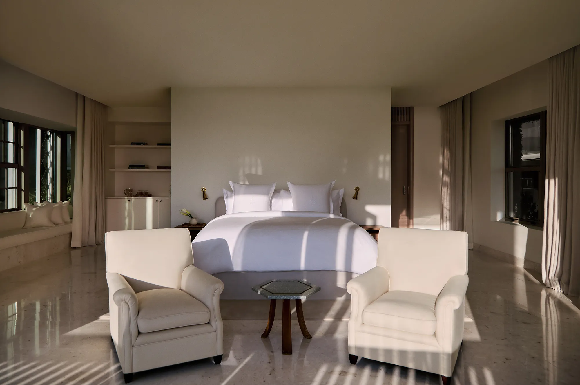 A spacious and elegantly appointed master bedroom with soft lighting and plush seating.