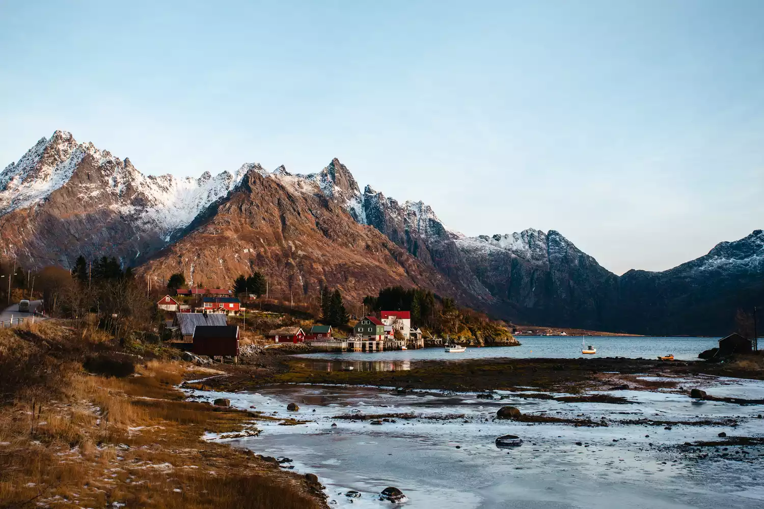 A coastal village with traditional cabins and rugged mountain peaks in the Lofoten Islands, Norway.