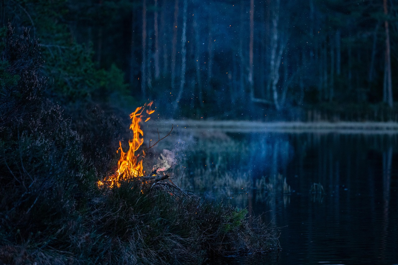 Friends gathered around a smokeless fire pit at a campsite during dusk.