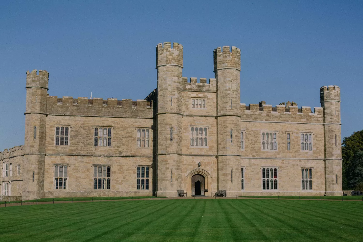 The stone exterior of Leeds Castle rising from its surrounding lake.