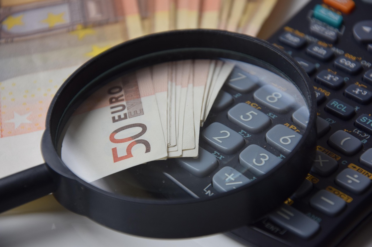 A notebook with travel expenses listed next to a calculator and foreign currency.