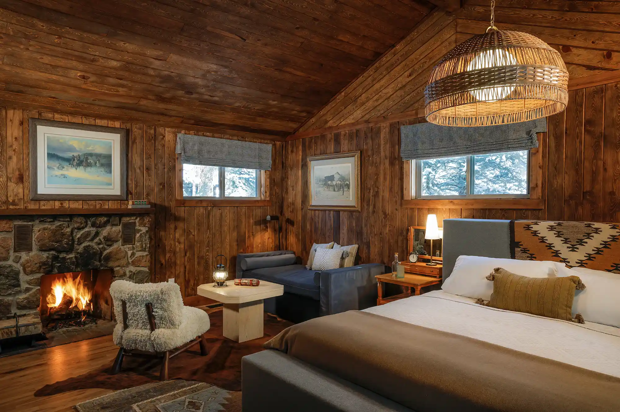 A luxury bedroom with a fireplace and large windows showing a winter forest view.