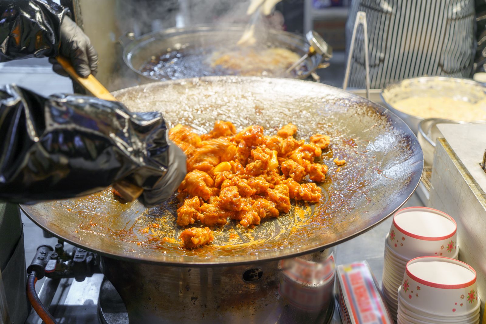 A chef deep-frying pieces of chicken in a professional fryer.