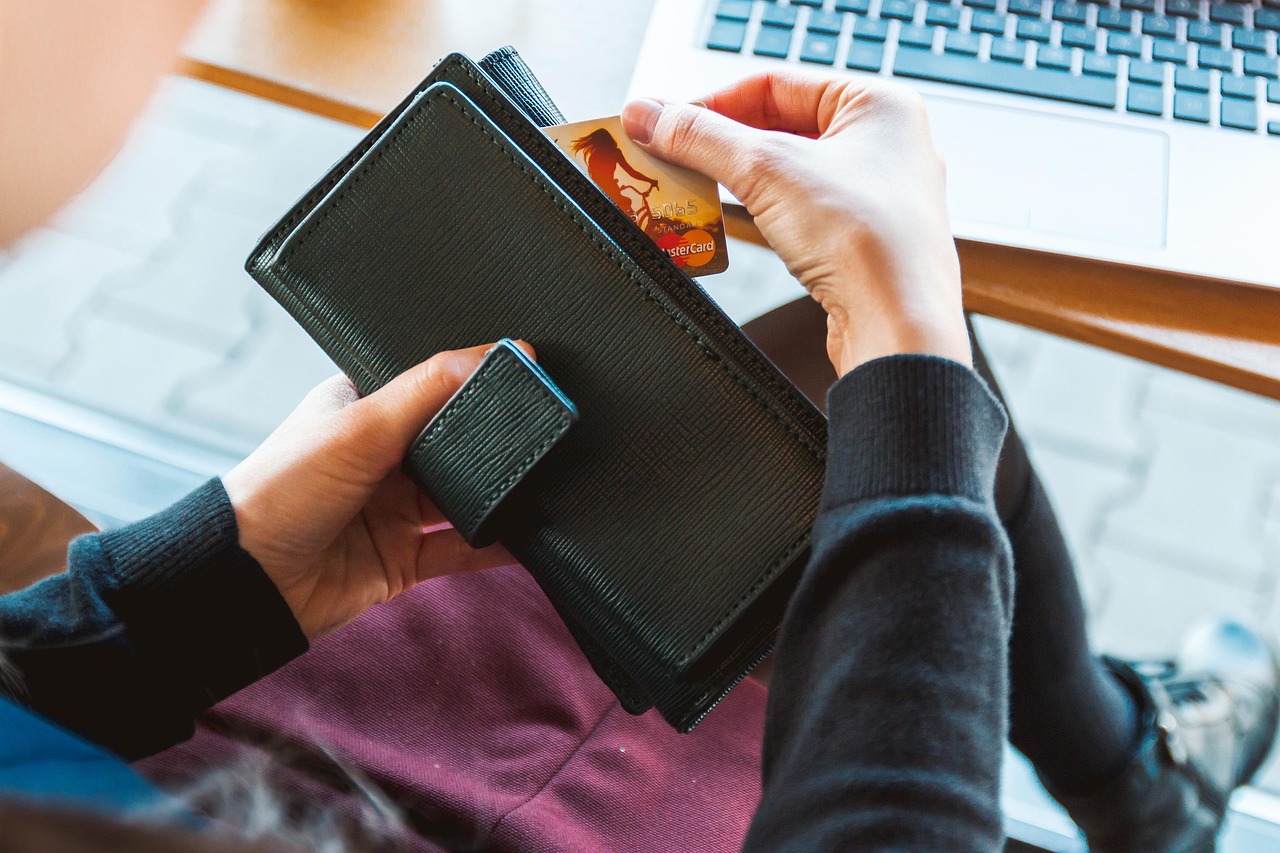 A person holding a credit card over a contactless payment terminal in a restaurant.