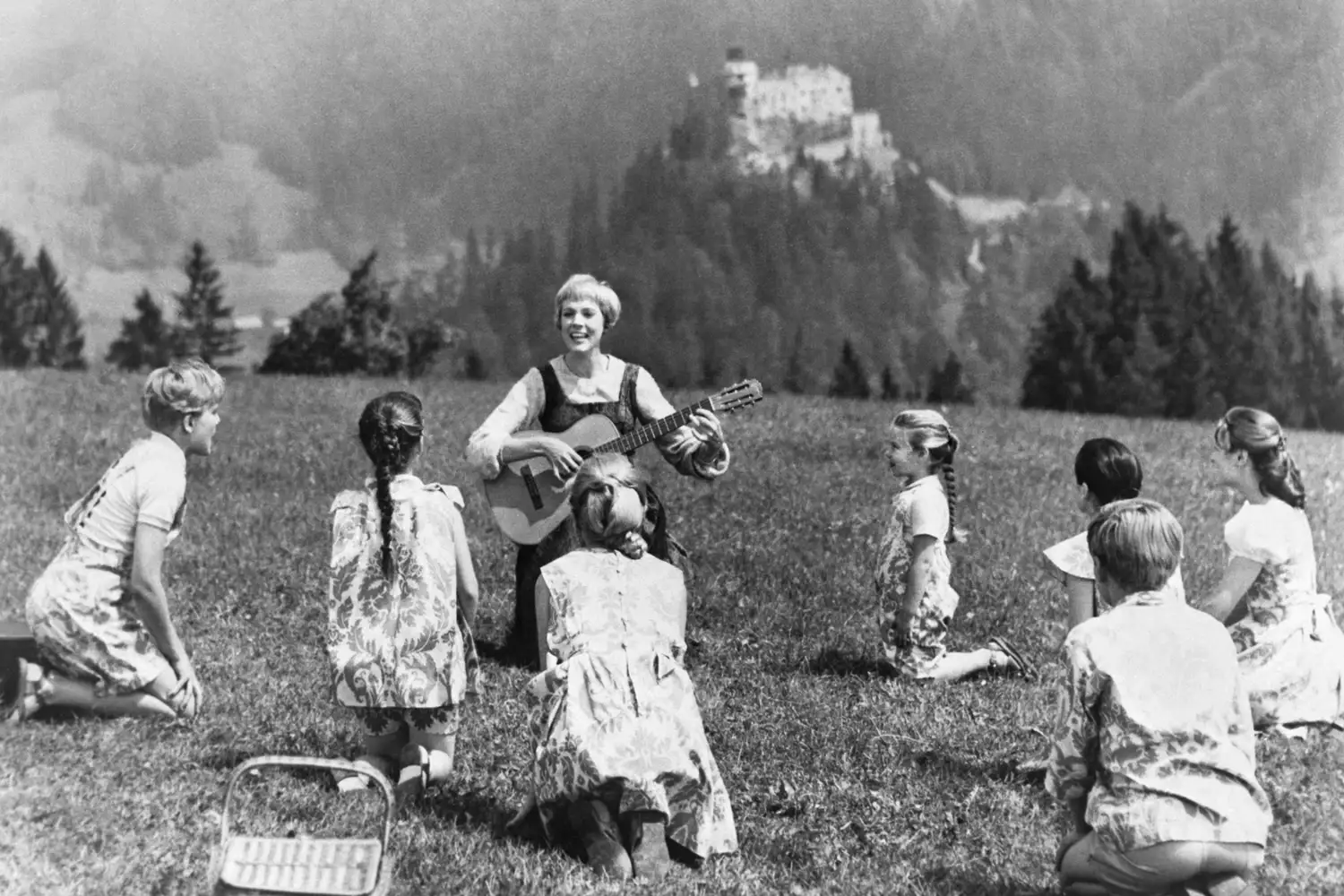 Julie Andrews as Maria performing outdoors with children in a scene from the movie.