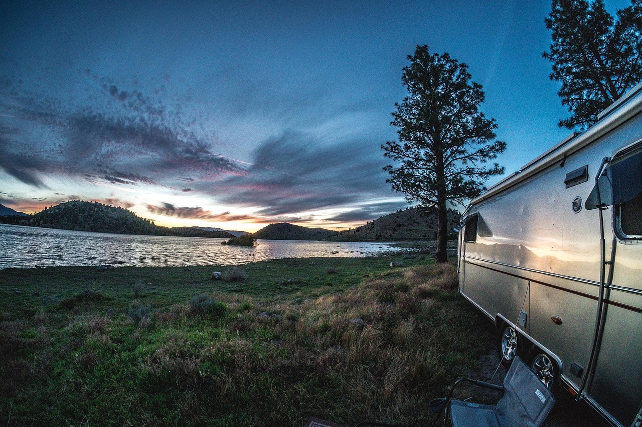A polished silver Airstream trailer parked in a scenic forest clearing