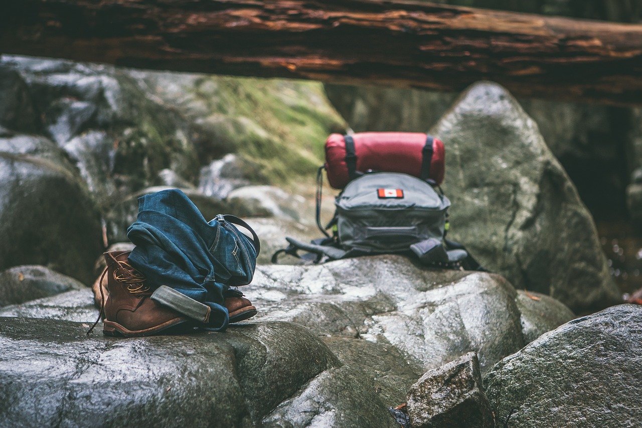 Various camping and hiking gear spread out on a rocky mountain terrain.