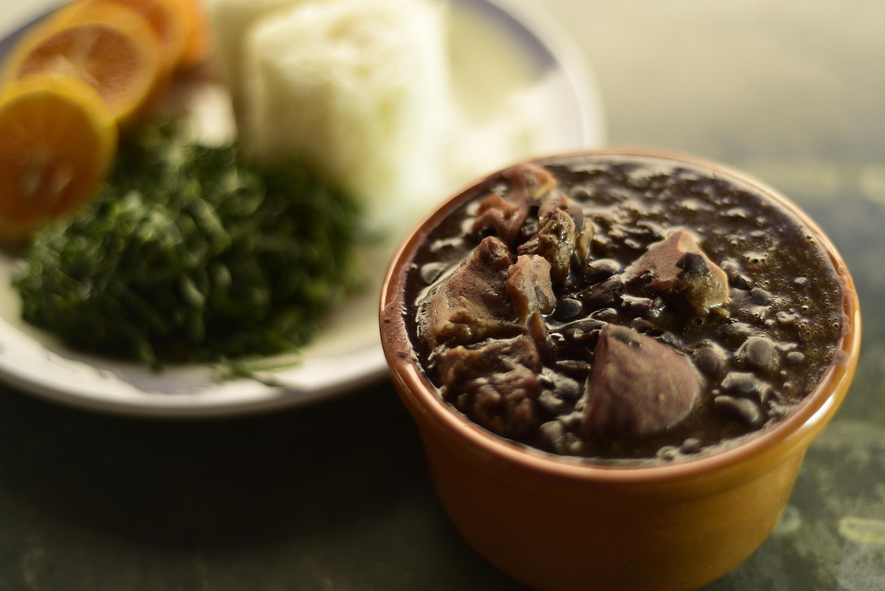 A traditional Brazilian feijoada served in a black clay pot with side dishes.