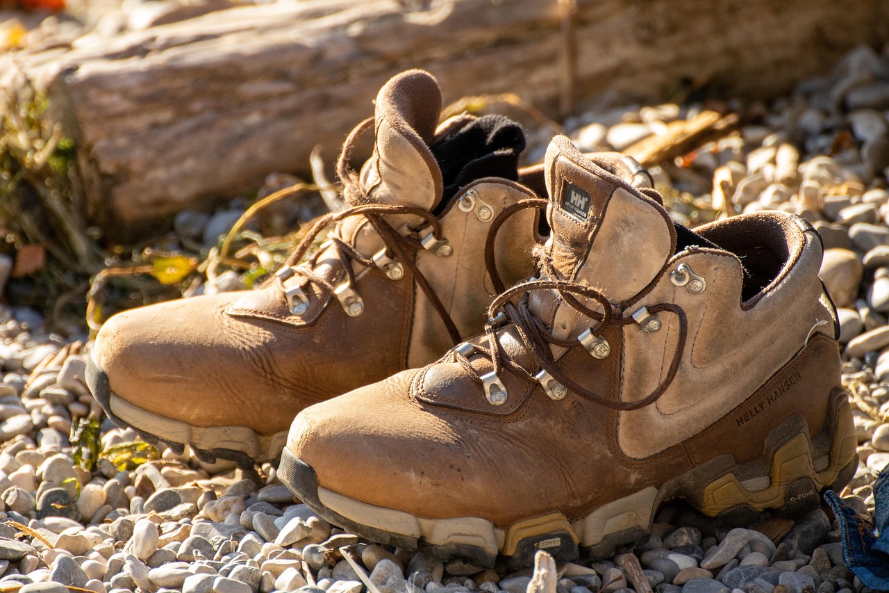 Close-up of professional hiking boots stepping on a rugged, rocky mountain trail.