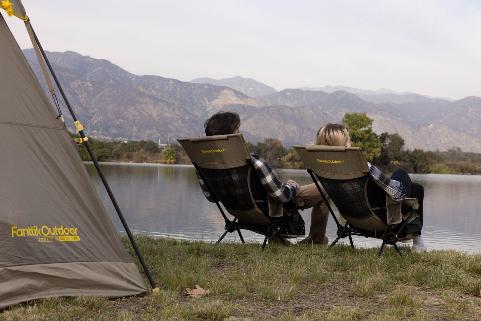 A person sitting peacefully by a calm lake during a camping trip.