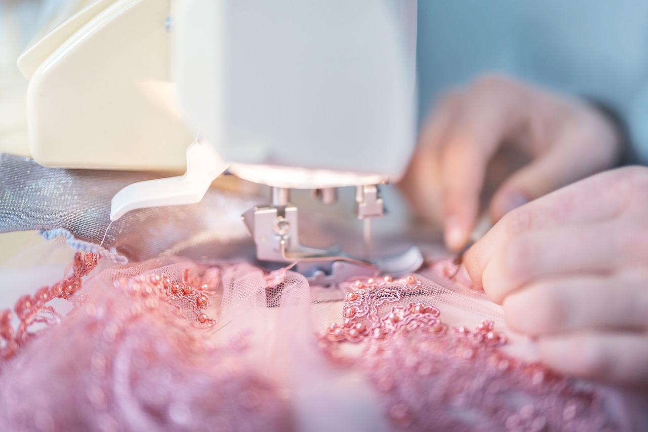 A close-up of a tailor working on a garment in a bright workshop