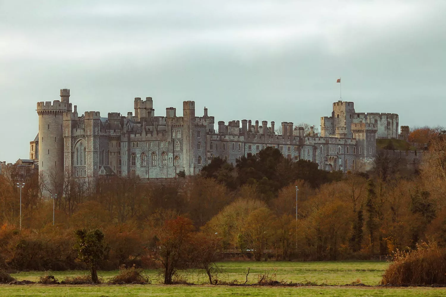 The majestic exterior facade of Arundel Castle sitting atop a green hill.