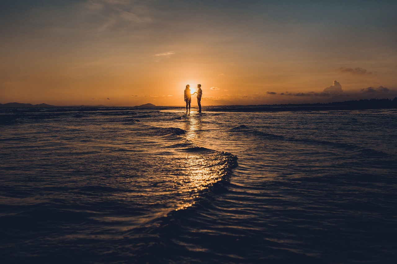 A private candlelit dinner set up on a white sand beach at sunset