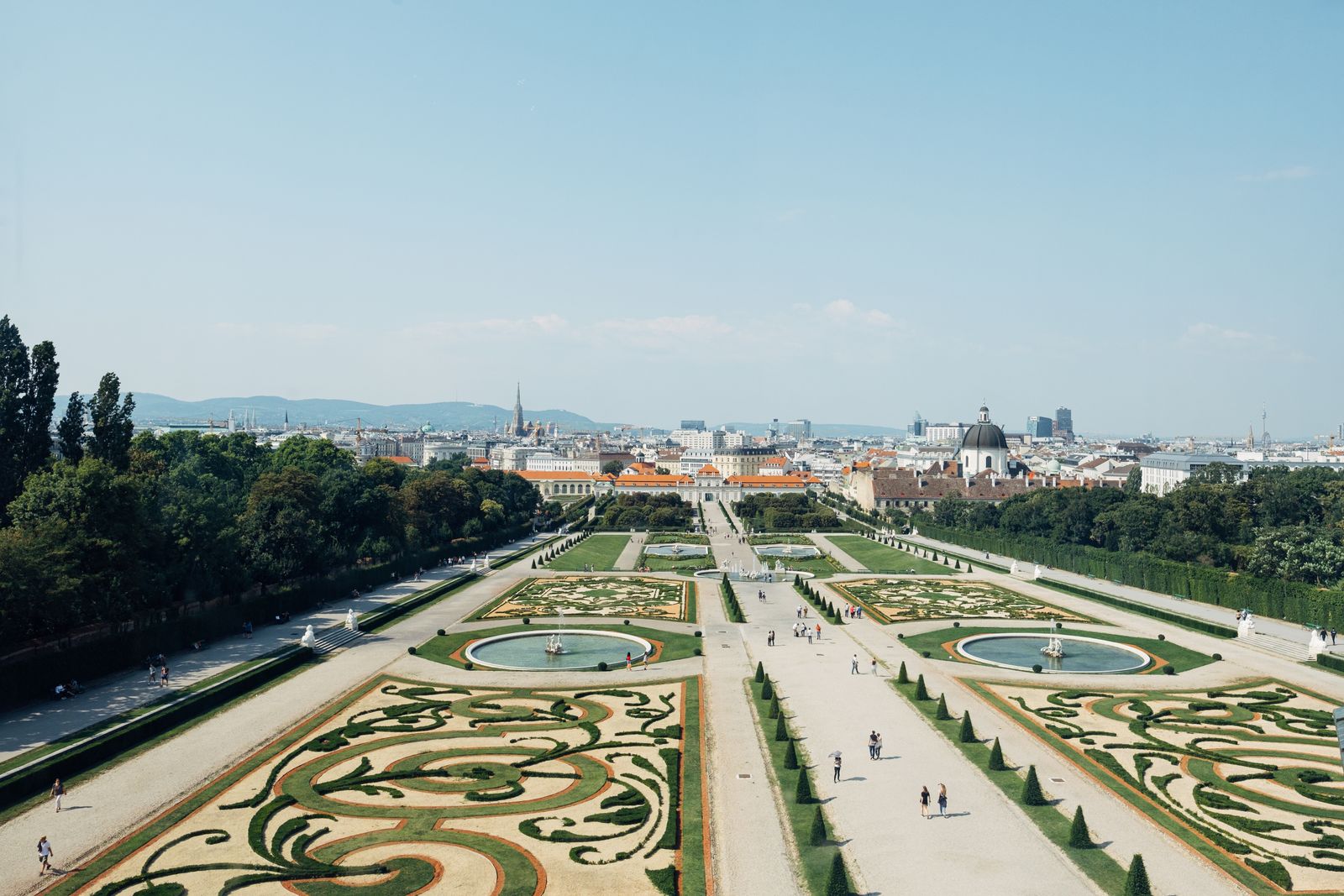 A sunlit historic town square in Athens with pedestrians and classical urban architecture.