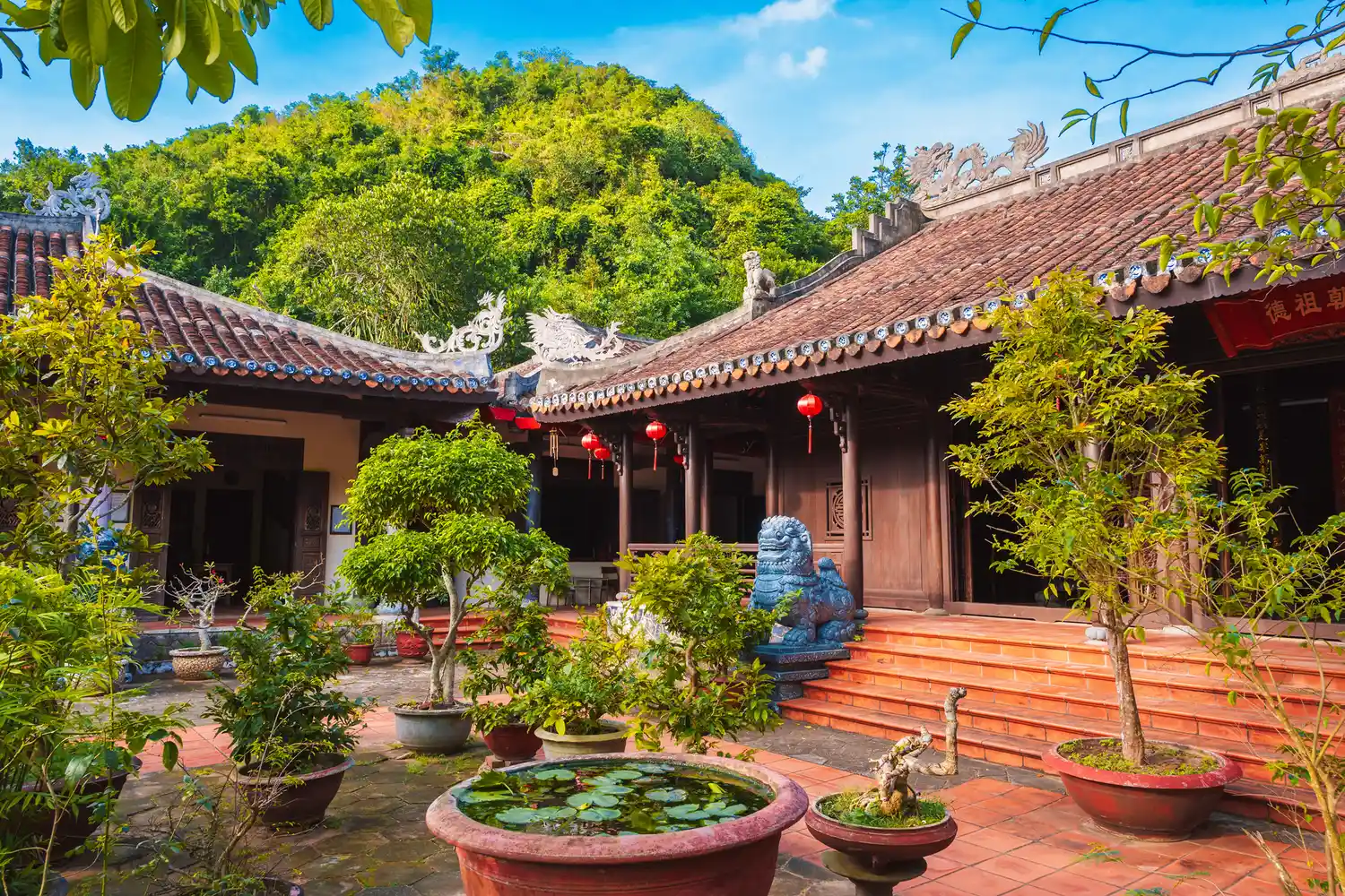 A quiet temple courtyard in Da Nang with lush green hills in the background.