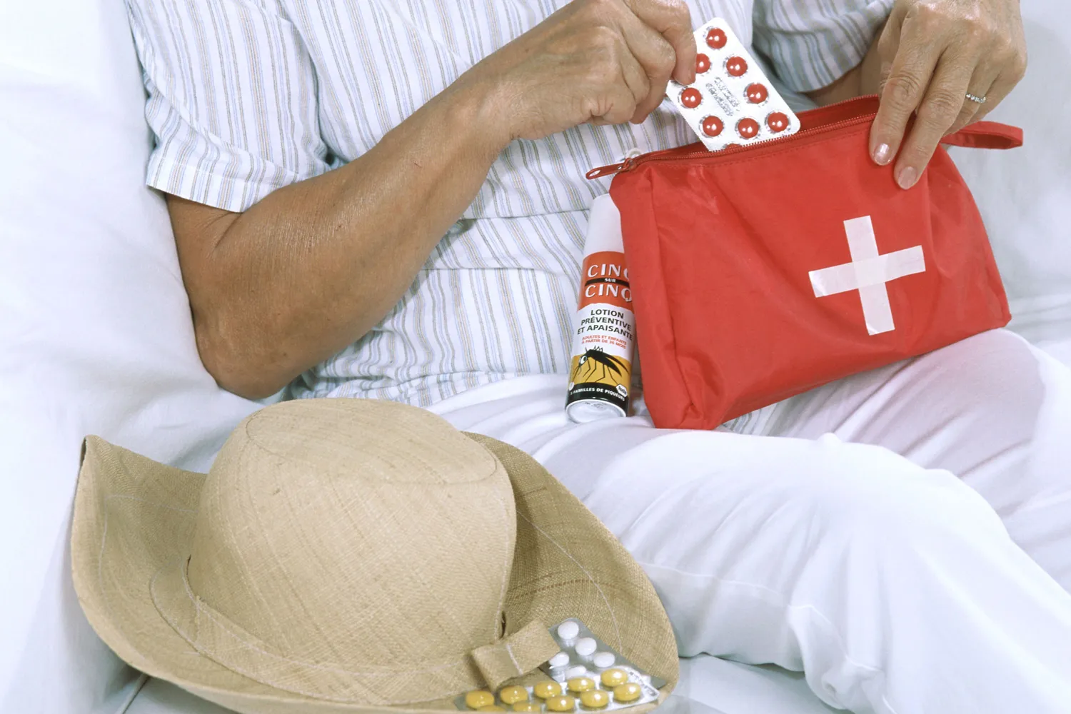 A person organizing various medication packs and a first aid kit for travel.